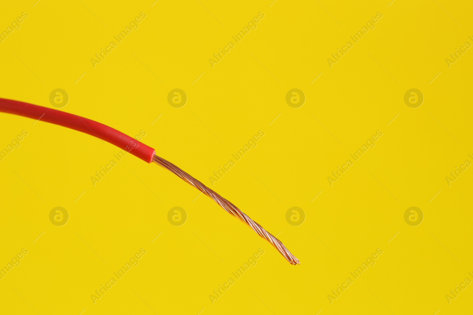 Photo of Red stripped electrical wire on yellow background, closeup