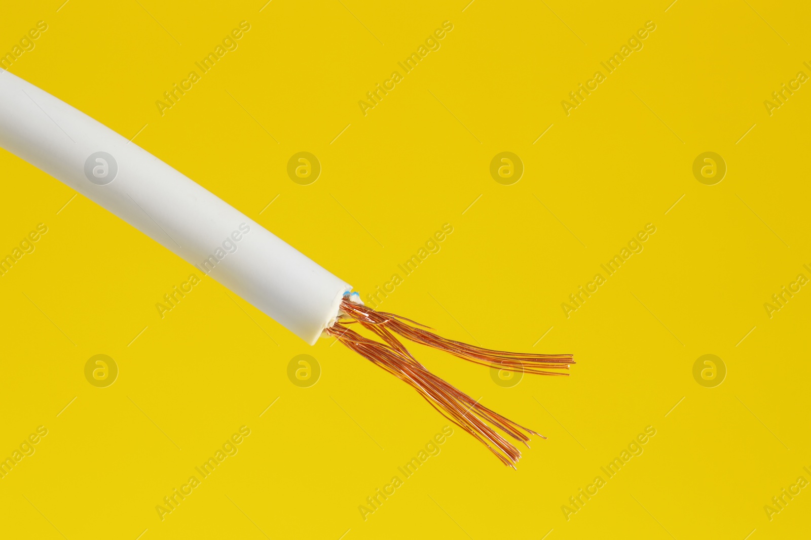 Photo of White stripped electrical wire on yellow background, closeup