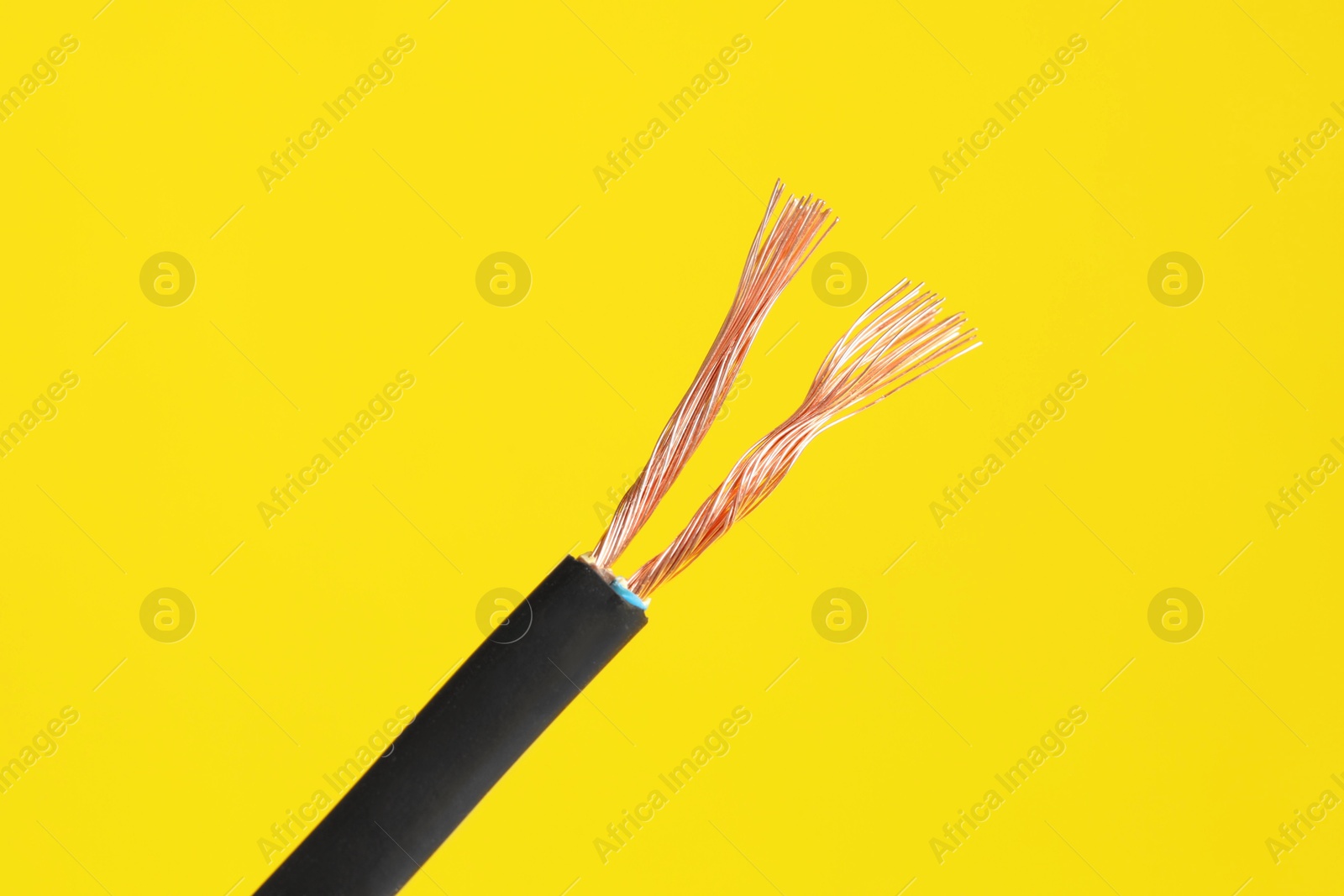 Photo of Black stripped electrical wire on yellow background, closeup