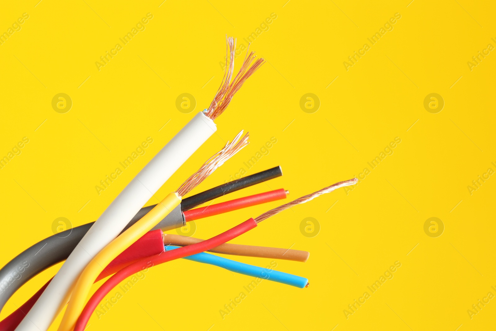 Photo of Many stripped electrical wires on yellow background, closeup