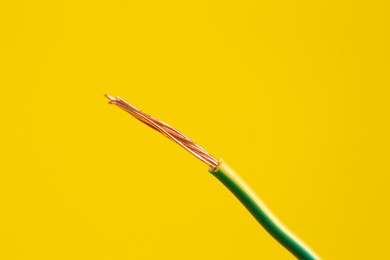 Photo of Stripped electrical wire on yellow background, closeup