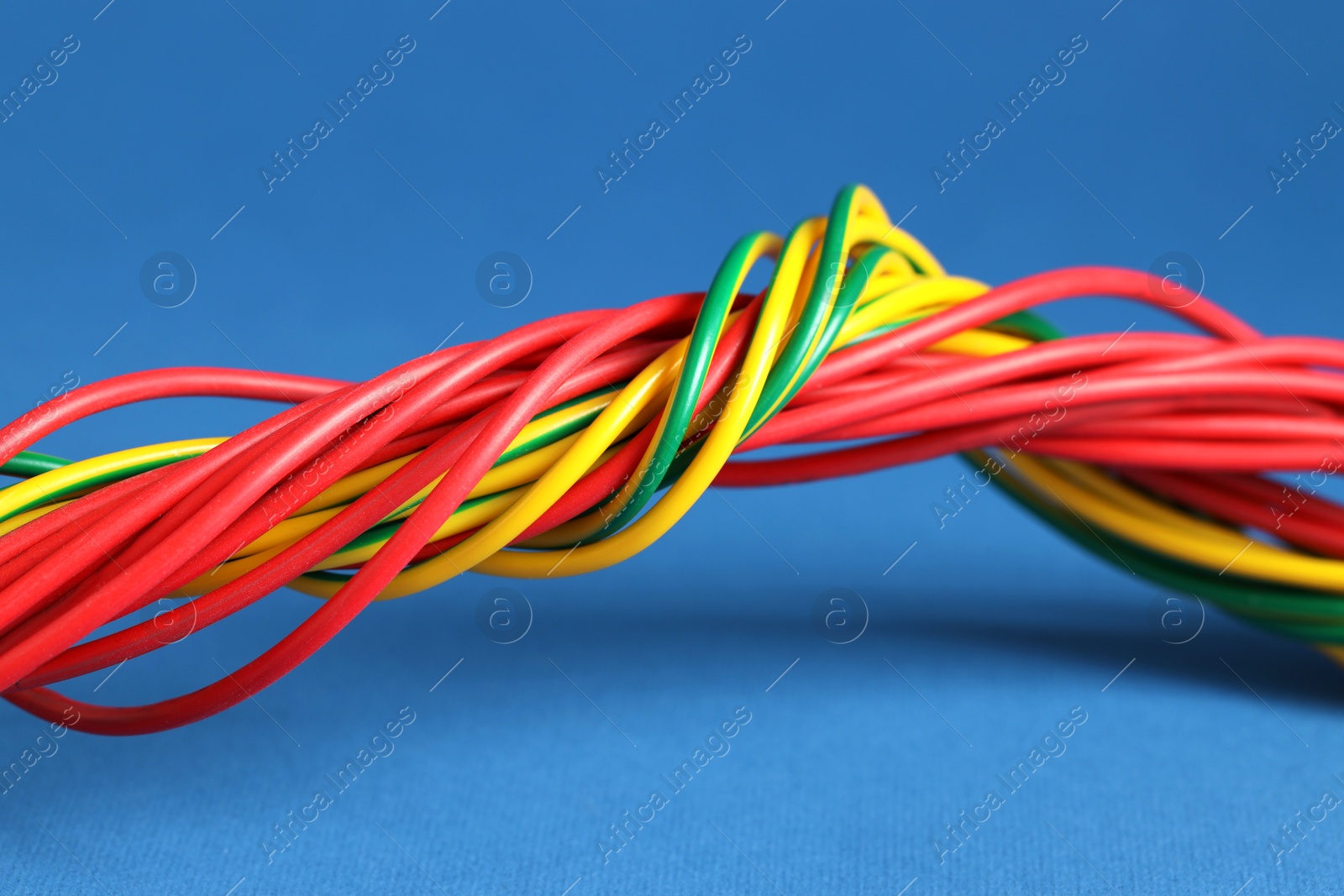 Photo of Many electrical wires on blue background, closeup