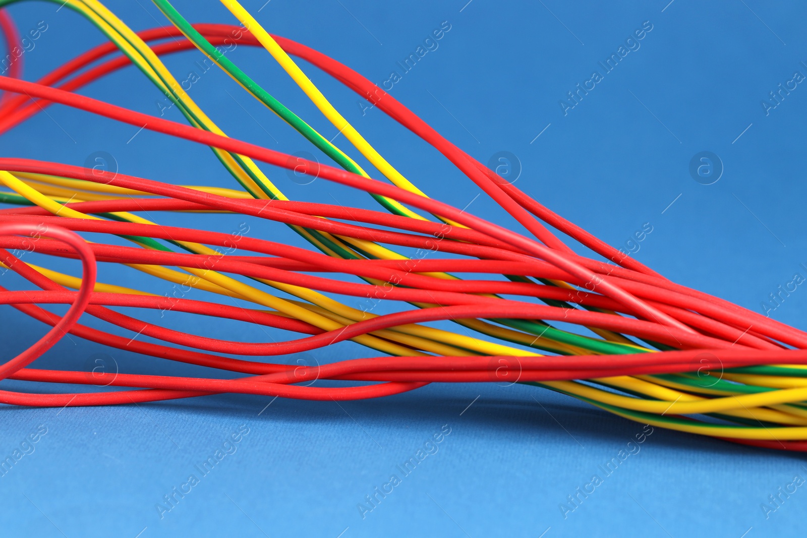 Photo of Many electrical wires on blue background, closeup