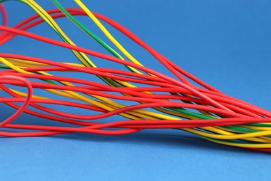 Photo of Many electrical wires on blue background, closeup