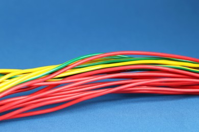 Photo of Many electrical wires on blue background, closeup