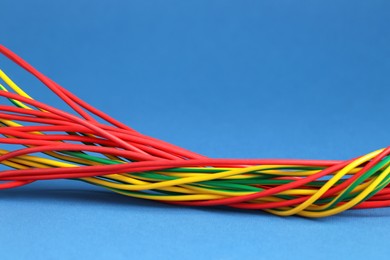 Photo of Many electrical wires on blue background, closeup