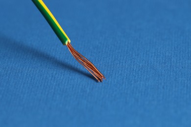 Photo of Stripped electrical wire on blue background, closeup. Space for text