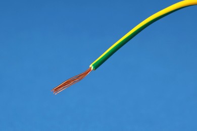 Photo of Stripped electrical wire on blue background, closeup