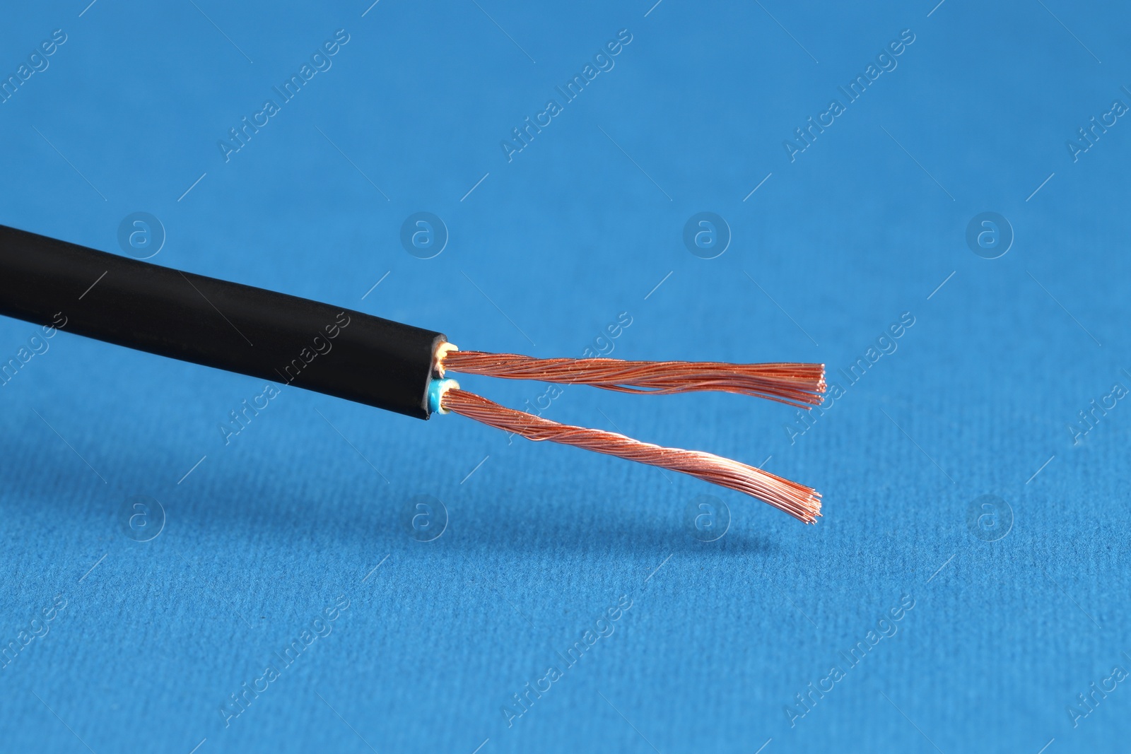 Photo of Black stripped electrical wire on blue background, closeup