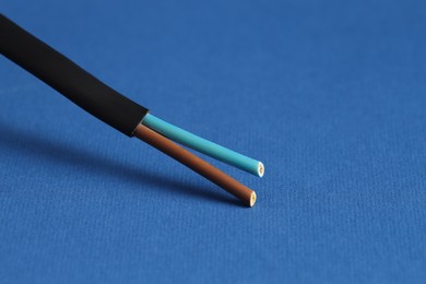 Photo of Black stripped electrical wire on blue background, closeup