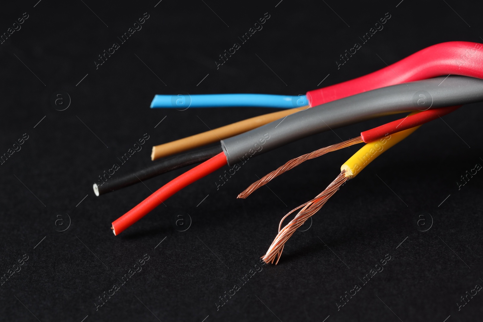 Photo of Many stripped electrical wires on black background, closeup