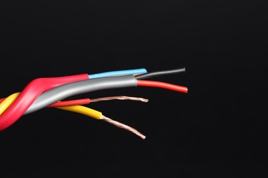 Photo of Many stripped electrical wires on black background, closeup