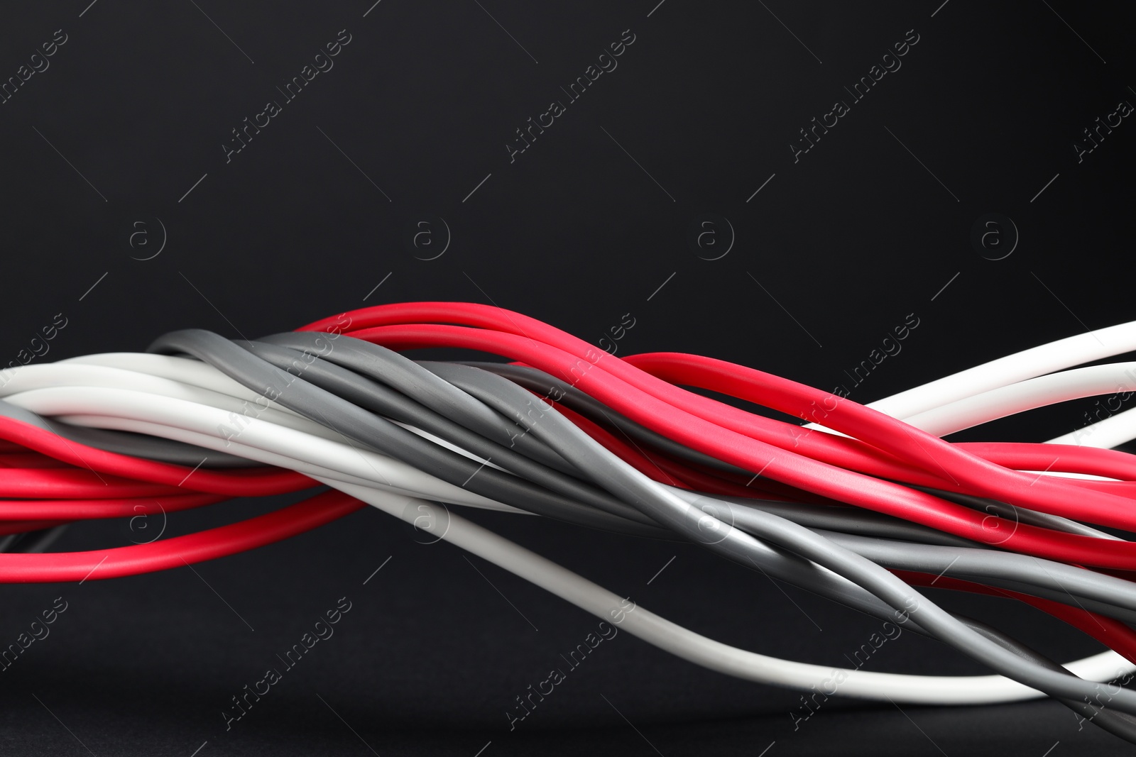 Photo of Many electrical wires on black background, closeup