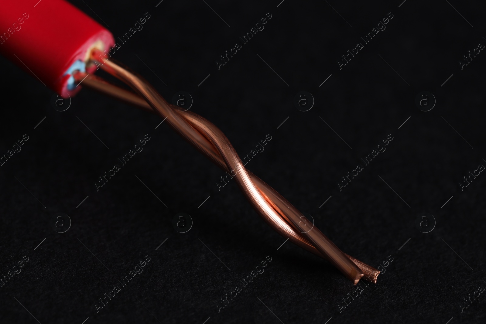 Photo of Red stripped electrical wire on black background, closeup