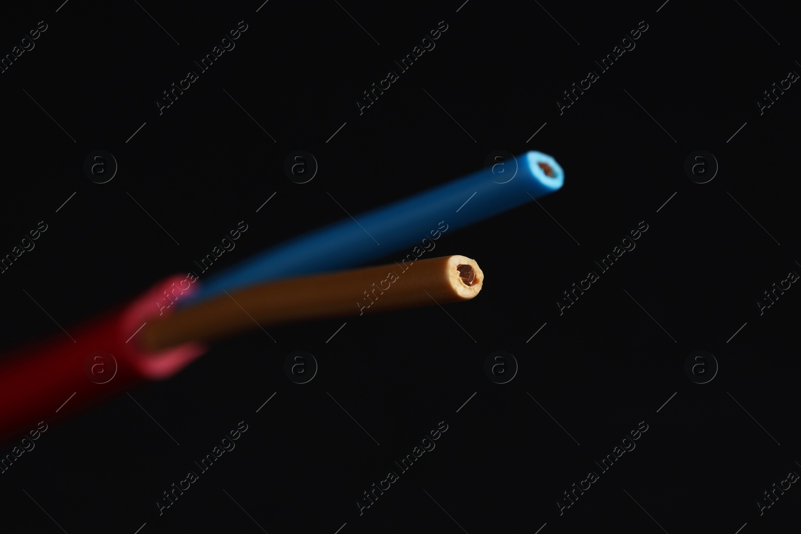 Photo of Red stripped electrical wire on black background, closeup