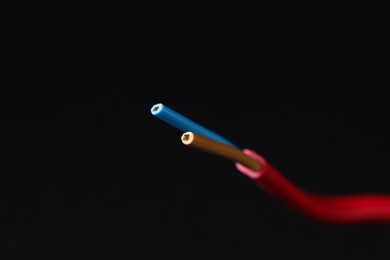 Photo of Red stripped electrical wire on black background, closeup