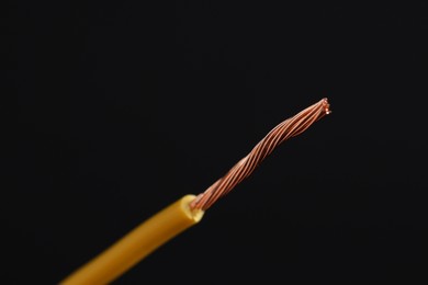 Photo of Yellow stripped electrical wire on black background, closeup. Space for text