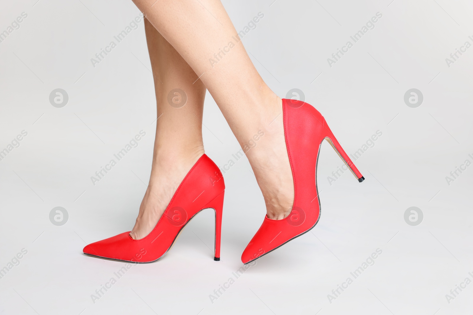 Photo of Woman wearing beautiful red high heeled shoes on white background, closeup