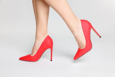 Photo of Woman wearing beautiful red high heeled shoes on white background, closeup