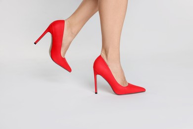 Photo of Woman wearing beautiful red high heeled shoes on white background, closeup