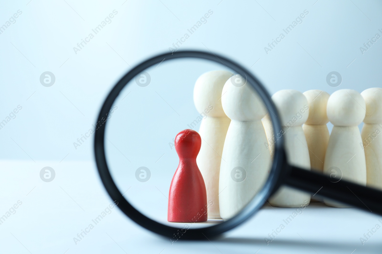 Photo of Human resources concept. Looking at wooden figures through magnifying glass on light background, closeup