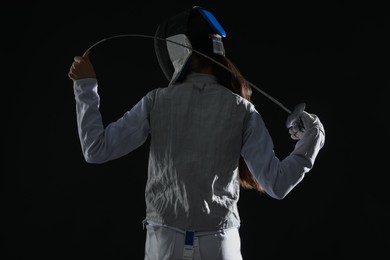 Photo of Fencer with epee on black background, back view