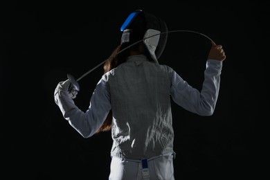 Photo of Fencer with epee on black background, back view