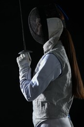 Photo of Fencer with epee on black background. Combat sport