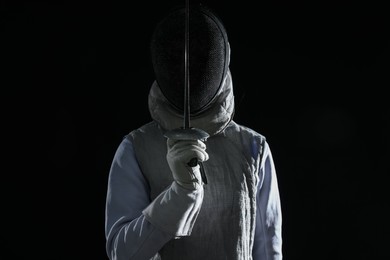 Photo of Fencer with epee on black background. Combat sport