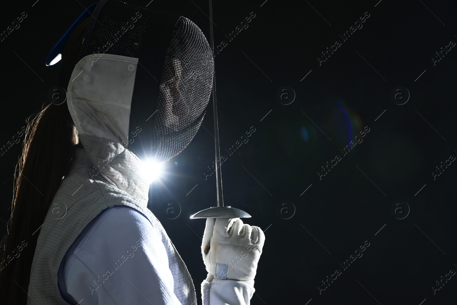 Photo of Fencer with epee on dark background, space for text