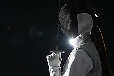 Photo of Fencer with epee on dark background, space for text