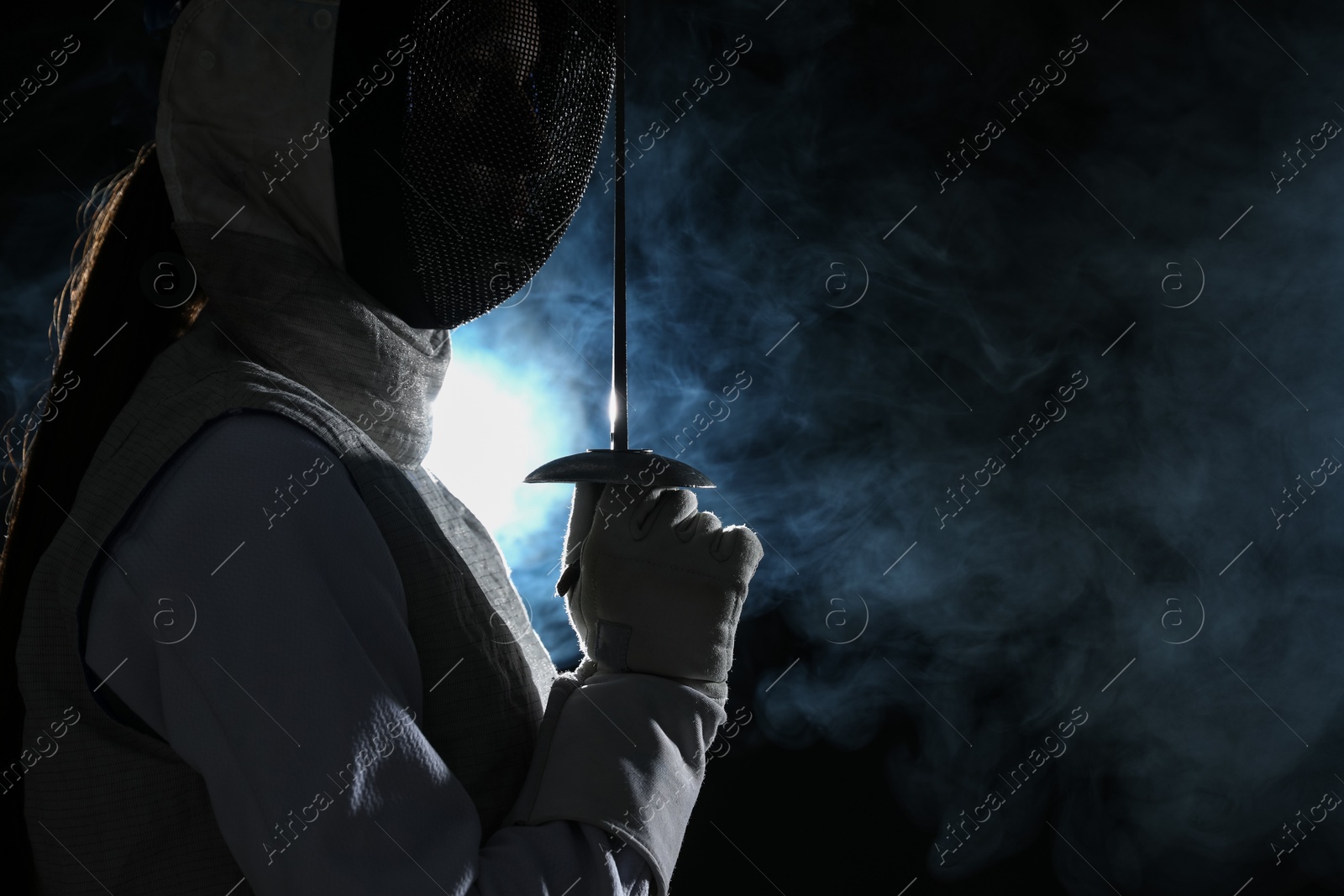 Photo of Fencer with epee in smoke on black background, space for text