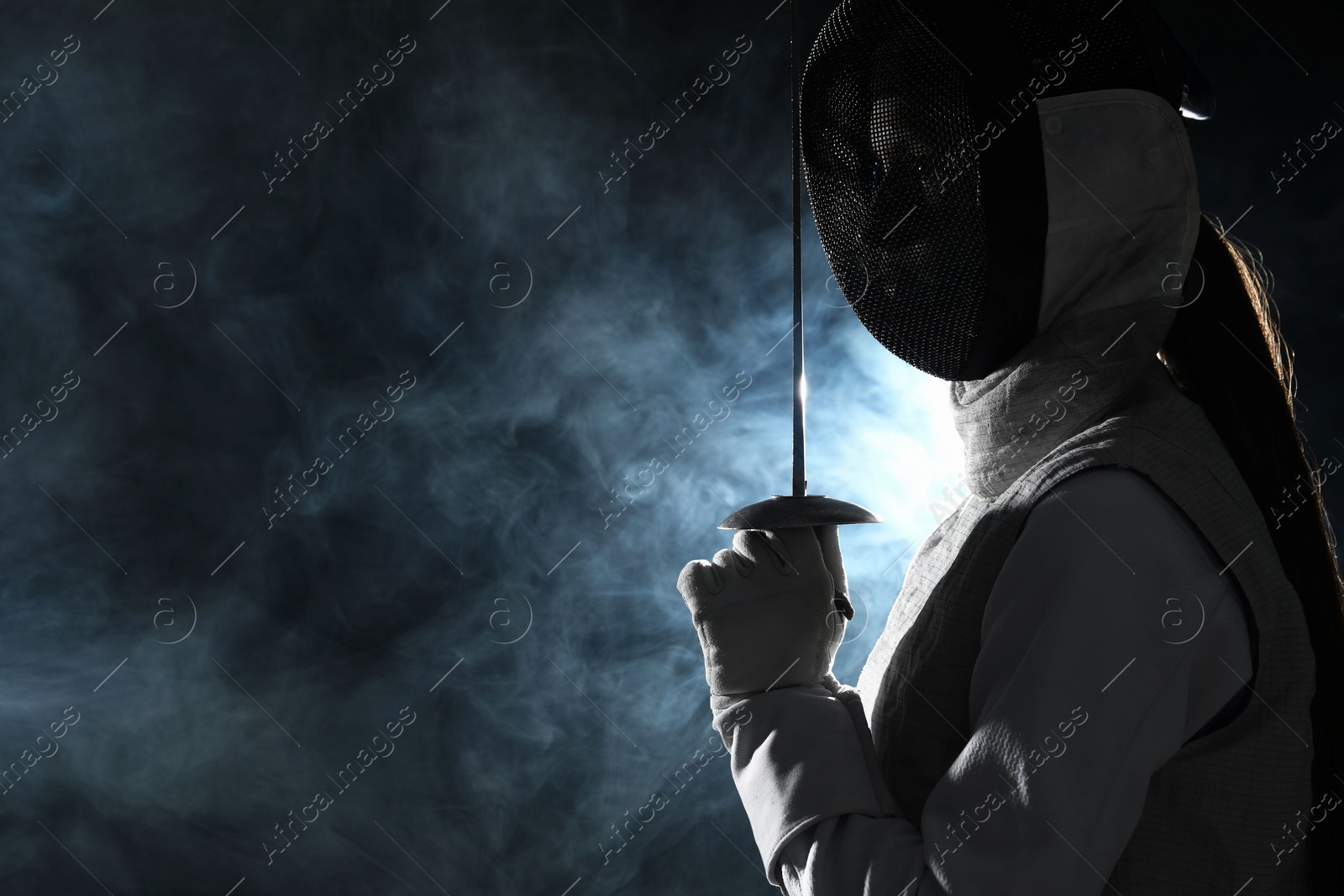 Photo of Fencer with epee in smoke on black background, space for text