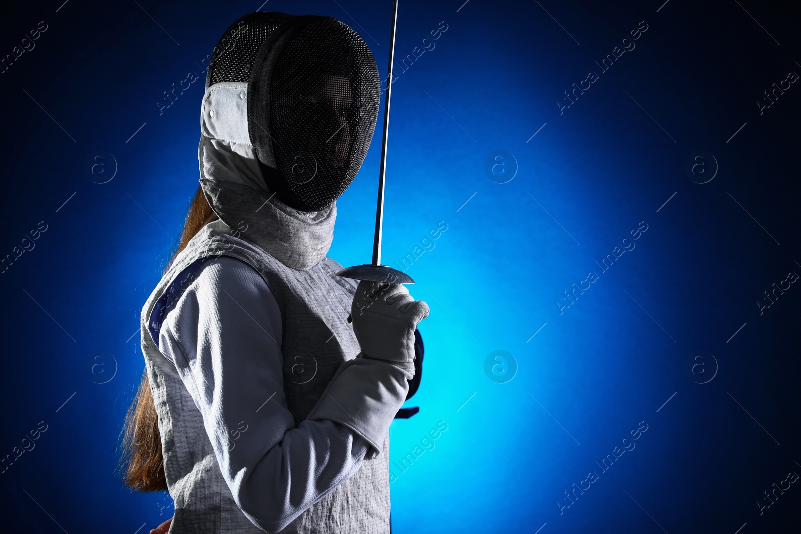 Photo of Fencer with epee on dark blue background, space for text