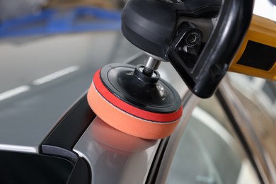 Photo of Man polishing car with orbital polisher indoors, closeup