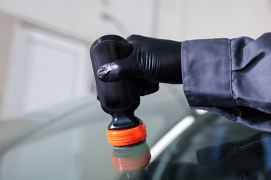 Photo of Man polishing car windshield indoors, closeup view