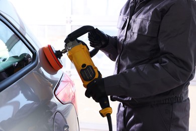 Photo of Man polishing car with orbital polisher indoors, closeup