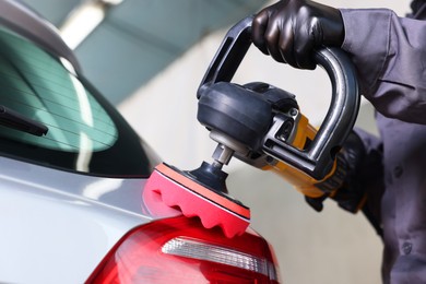 Photo of Man polishing car rear light with orbital polisher indoors, closeup