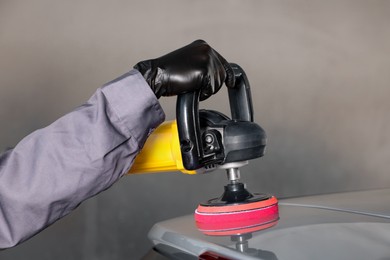 Man polishing car with orbital polisher indoors, closeup