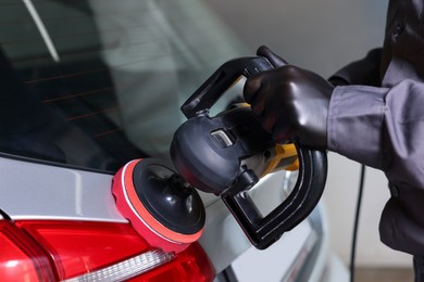 Photo of Man polishing car with orbital polisher indoors, closeup