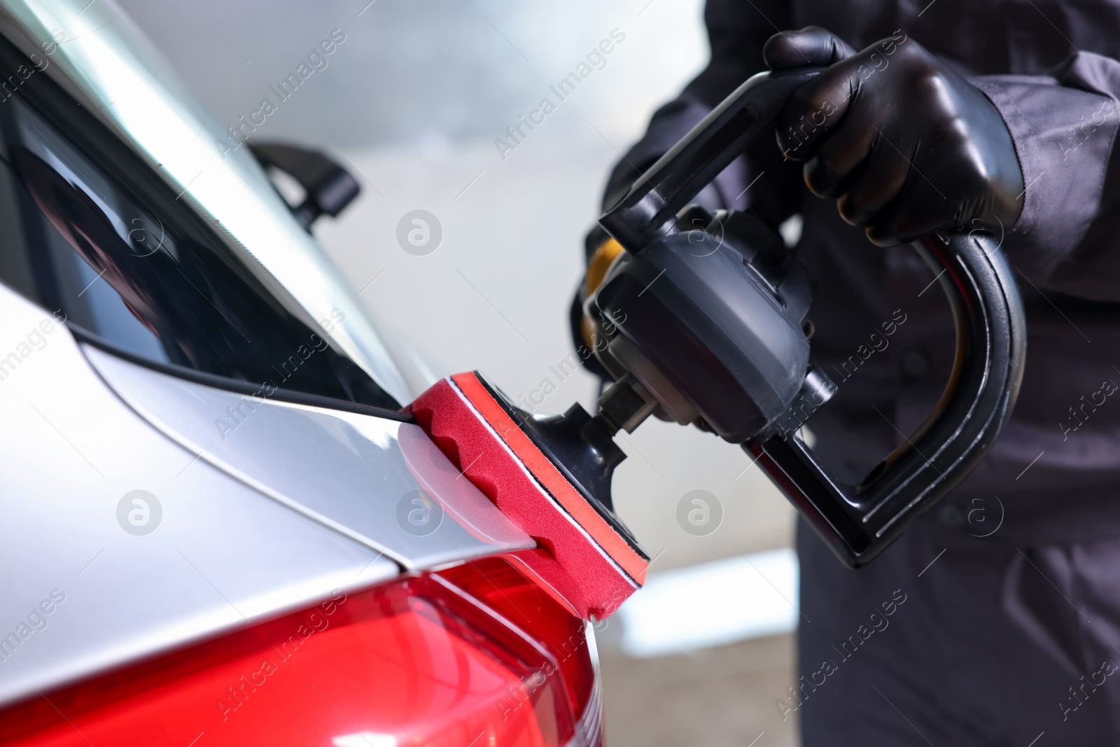 Photo of Man polishing car with orbital polisher indoors, closeup