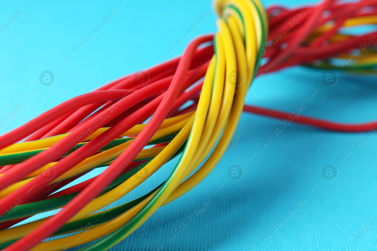 Photo of Many color electrical wires on light blue background, closeup