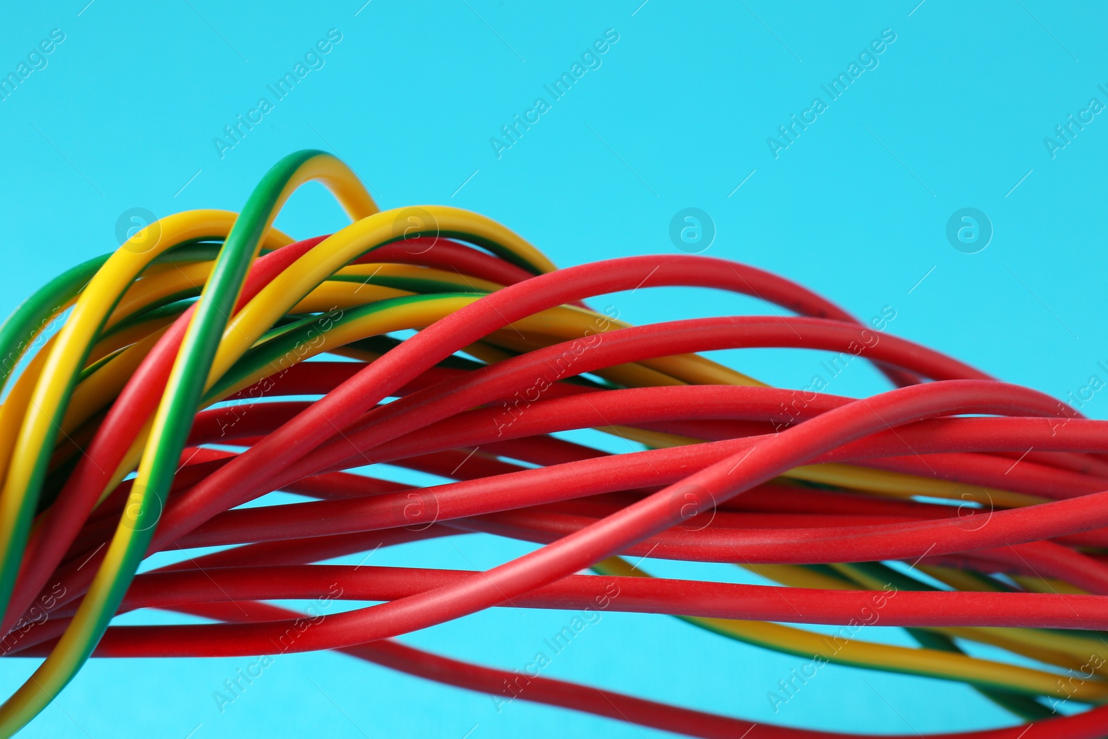 Photo of Many color electrical wires on light blue background, closeup