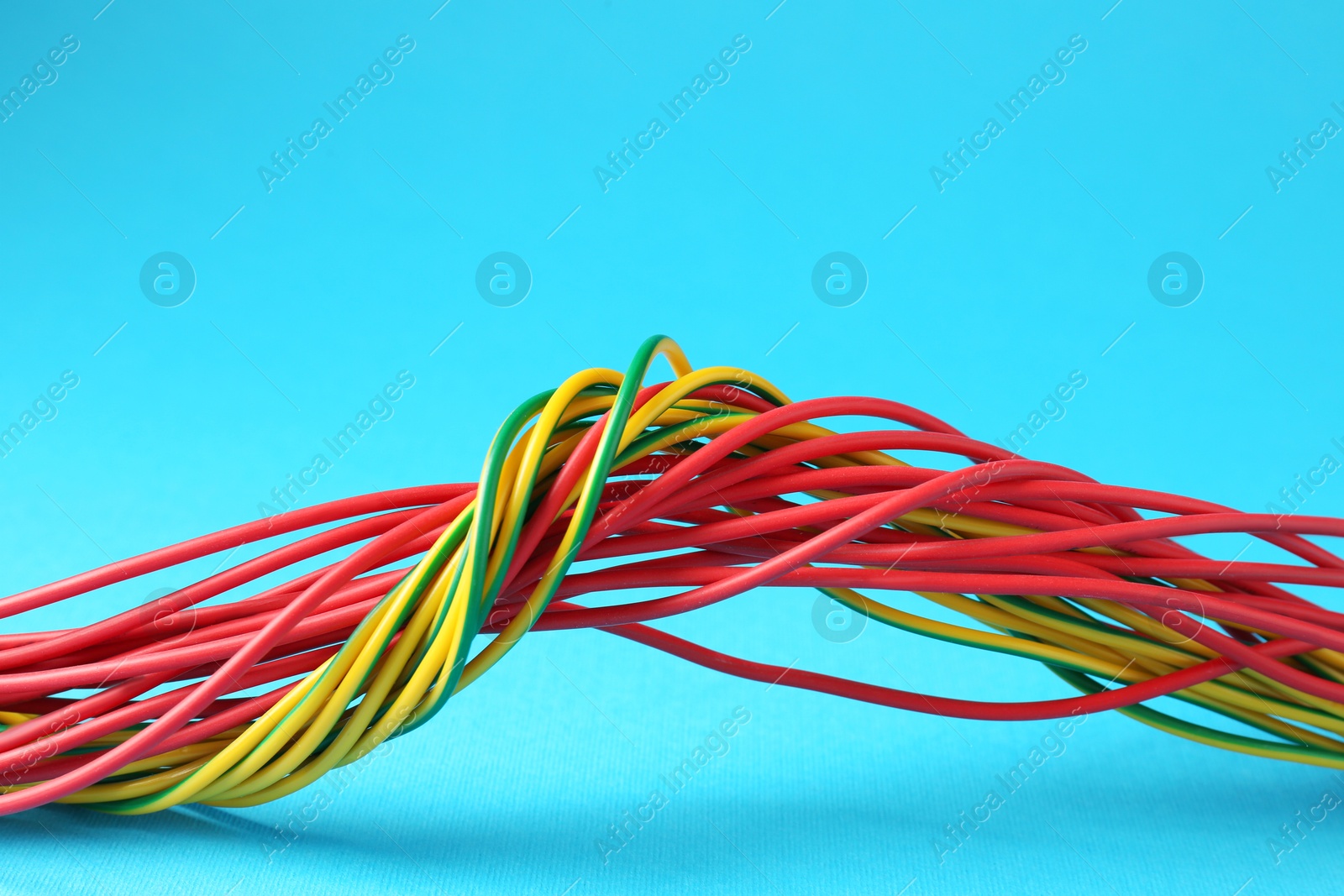 Photo of Many color electrical wires on light blue background, closeup