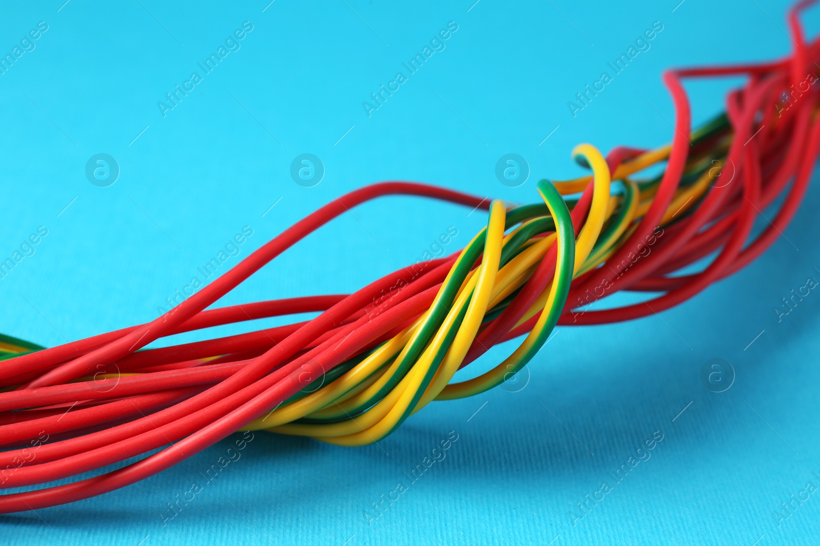 Photo of Many color electrical wires on light blue background, closeup