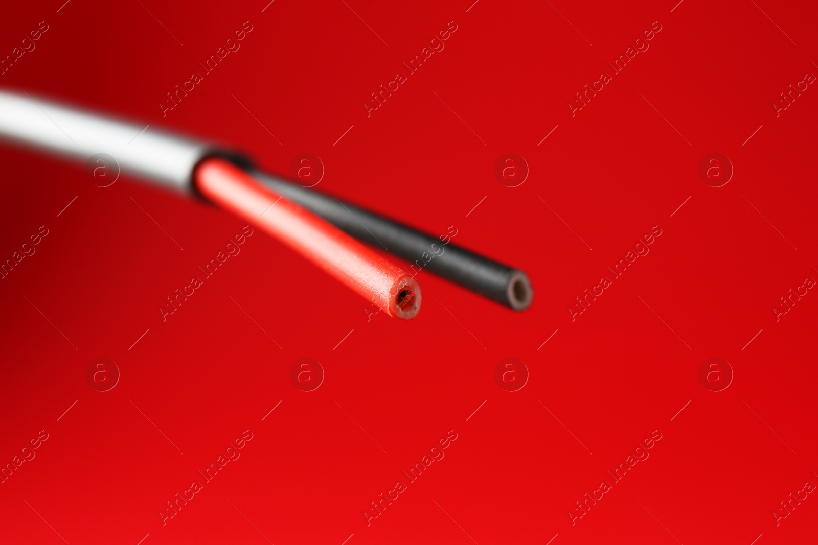 Photo of Stripped electrical wire on red background, closeup. Space for text