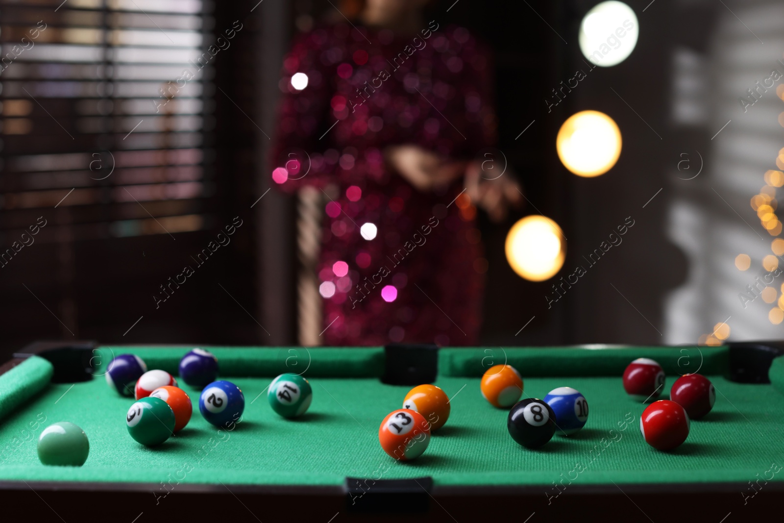 Photo of Woman near green billiard table with many colorful balls indoors, selective focus