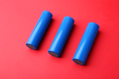 Photo of Three AA cell batteries on red background, closeup