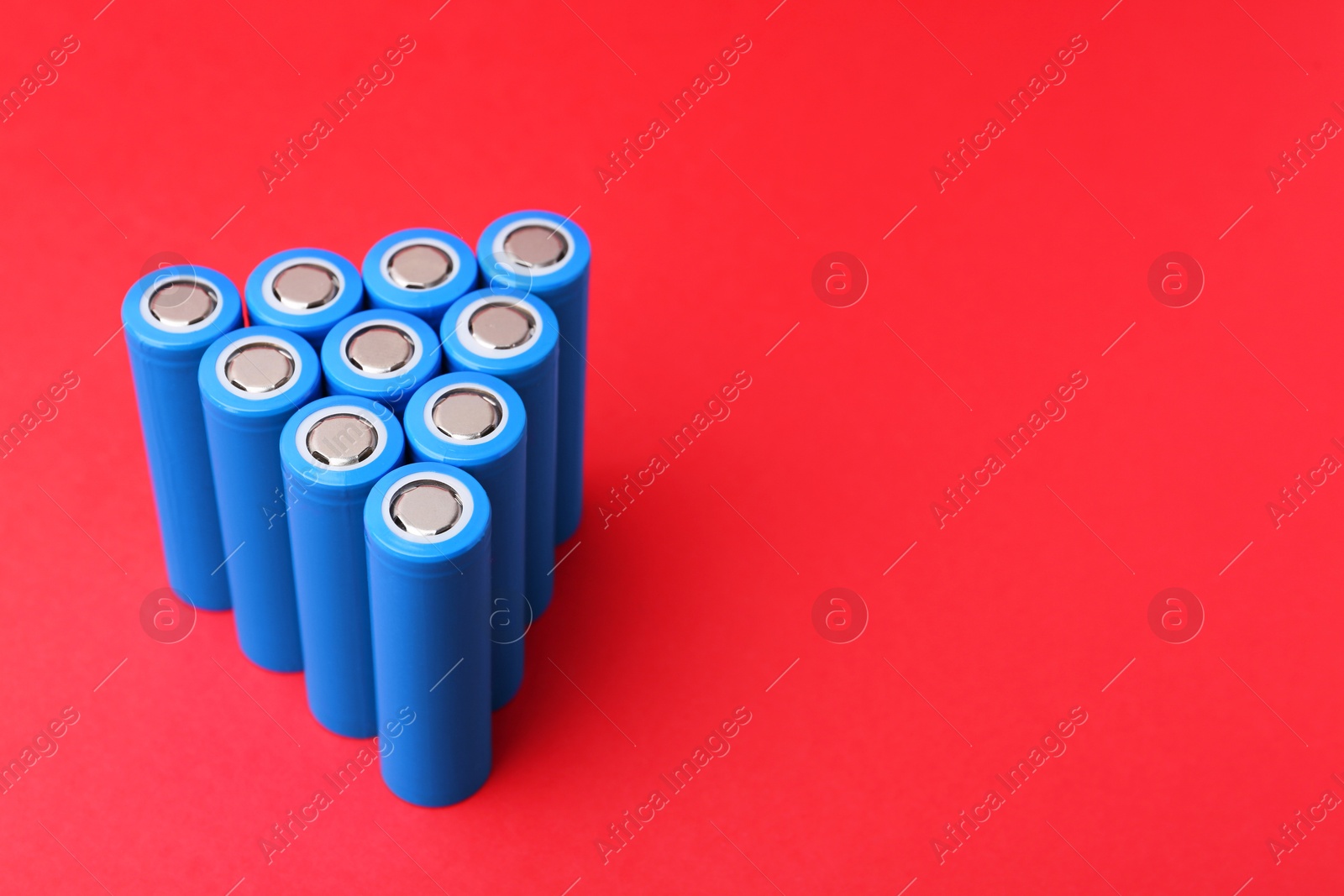 Photo of Many AA cell batteries on red background, closeup. Space for text