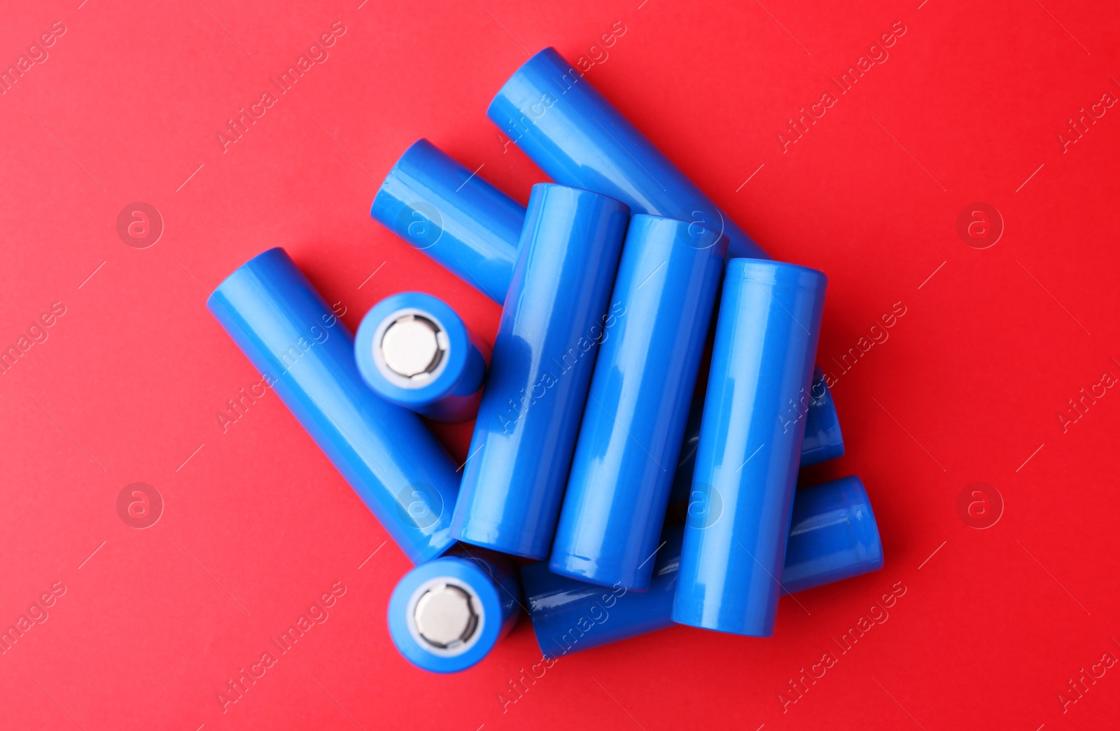 Photo of Many AA cell batteries on red background, top view